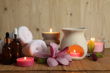 Aromatherapy. Scented candles, bottles, flower and towels on table