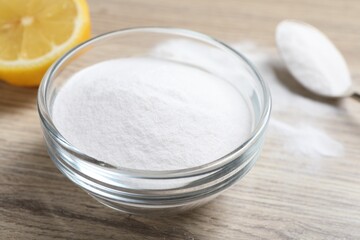 Baking soda and lemon on wooden table, closeup