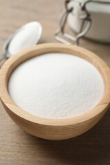 Baking soda in bowl on wooden table, closeup