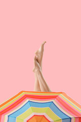 Young woman with umbrella on pink background. Travel concept
