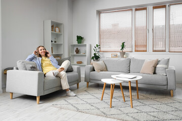 Young woman talking on mobile phone on sofa in light living room