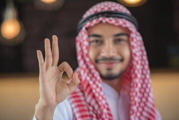 An Arab man in traditional clothing giving the OK sign.