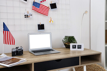 Interior of light office with workplace, laptop and USA flags