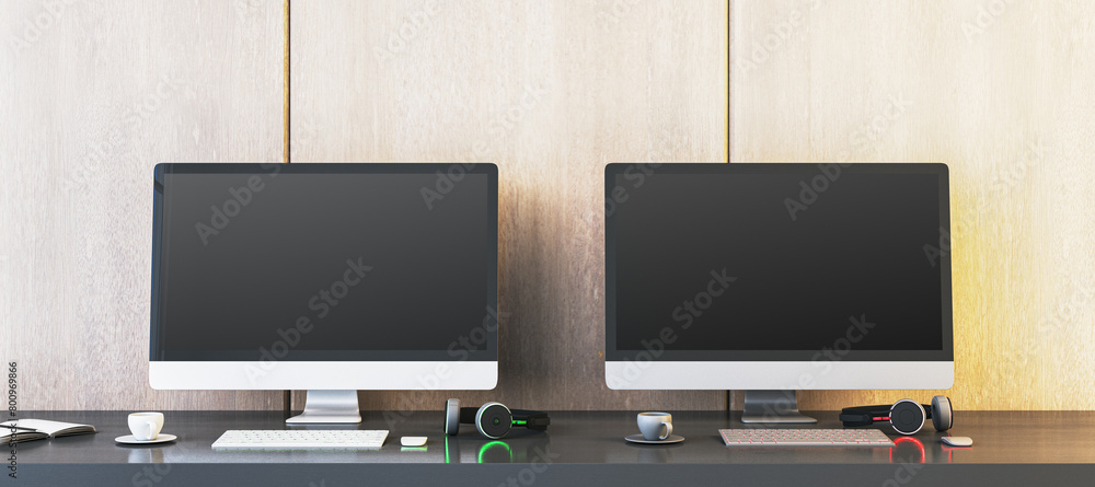 Poster two empty gaming computer monitors on desk with coffee cups and headsets. place for your advertiseme