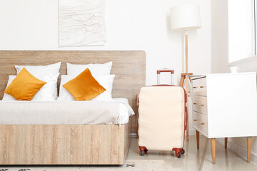 Interior of modern hotel room with suitcase near bed