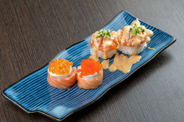 A plate of sushi with salmon roe, salmon, and spicy salmon.