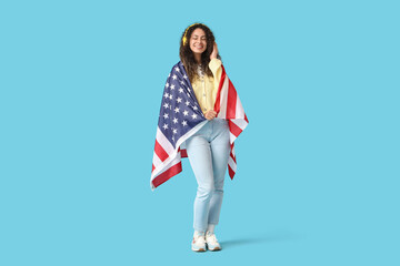 Young African-American woman in headphones with USA flag on blue background