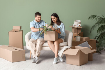 Young happy couple unpacking belongings on white sofa in their new house