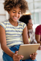 Happy african american preeteen girl using digital tablet for education, fun at home. Family concept