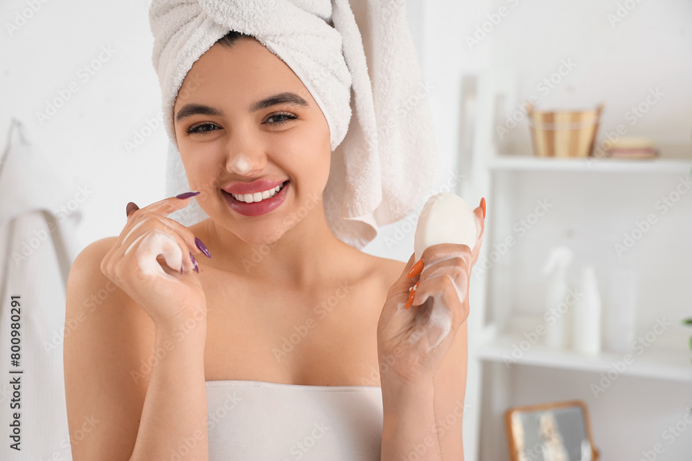 Sticker Young woman washing her face with soap in bathroom, closeup