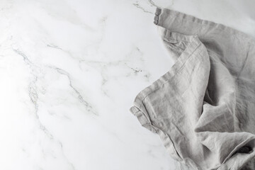 Wrinkled light grey pure linen towel on empty white marble board.Wrinkled light grey pure linen...