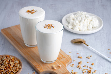 Kefir, buttermilk or yogurt, cottage cheese with granola. Yogurt in glass on white wooden...
