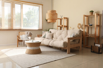 Interior of living room with comfortable sofa, coffee table, armchair and lamp