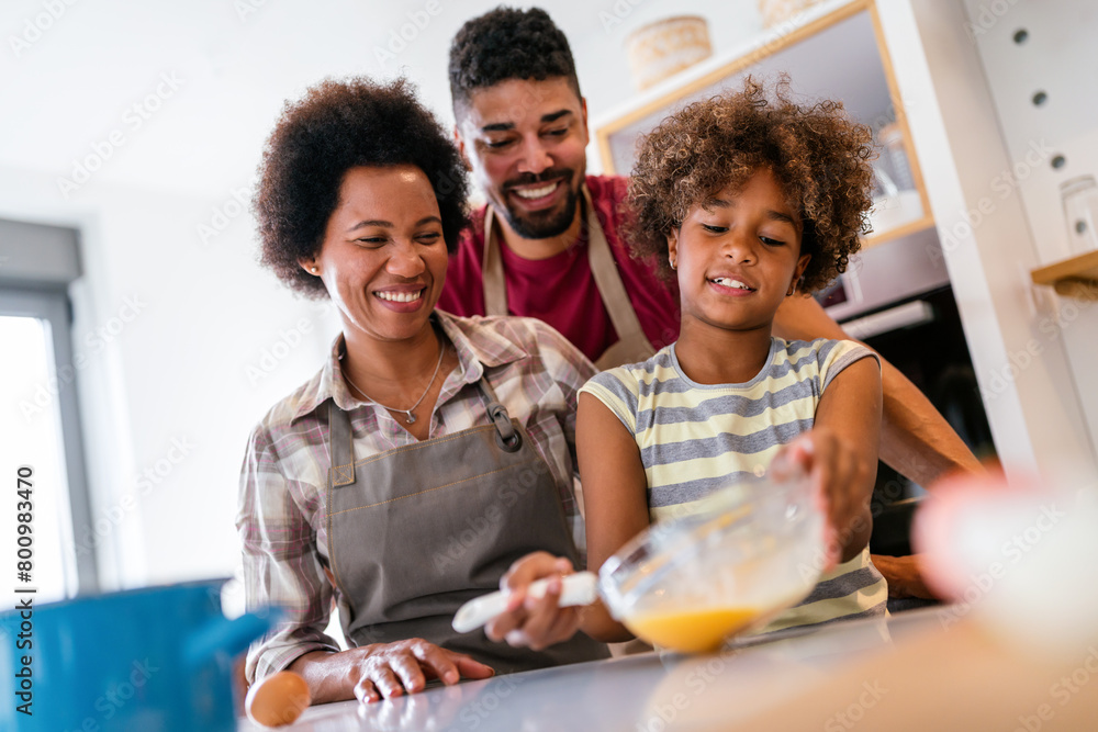 Wall mural Overjoyed young african american family with kid have fun cooking at home together,