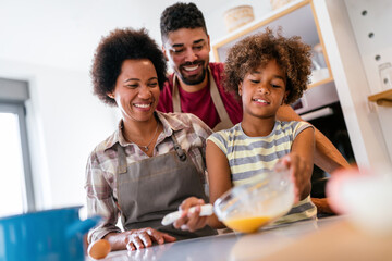 Overjoyed young african american family with kid have fun cooking at home together,