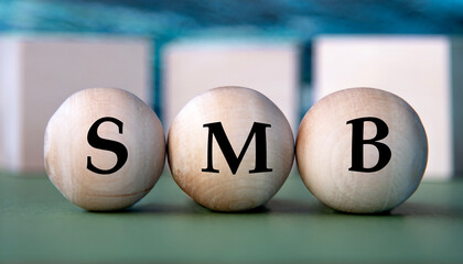 SMB - acronym on wooden balls on the background of wooden large cubes