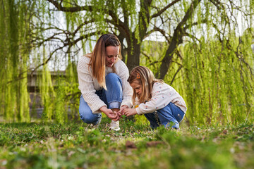 Mother and daughter playing in the grass in their weekend walk