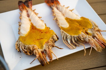 Large river prawns are grilled and cut in half to reveal the meat and fat on the prawn's head.
