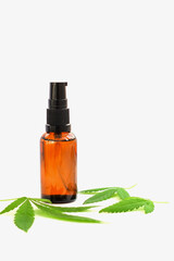 Marijuana leaves and a bottle on a white background, cannabis cosmetic oil