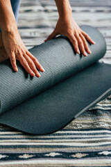 Close up of woman closing her yoga mat after finishing healthy lifestyle training session alone at...