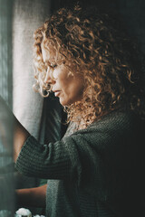 Sadness worried woman inside home near the window. Bad unhappy day. Side view of female people sad...