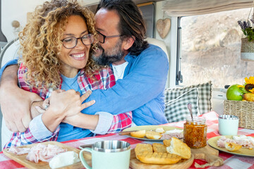 Excited and joyful couple in love inside camper van during lunch time. Cheerful woman and man...