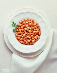 Dish of cooked chickpeas with tomato sauce on marble background