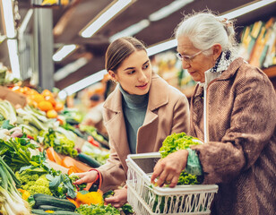 Elderly lady daughter with young woman mother at the grocery store buying choosing vegetable