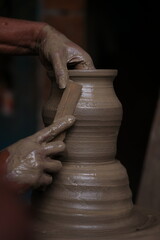 The potter works on a pottery wheel to made of soft colored clay, retro style toned Clay pots with...