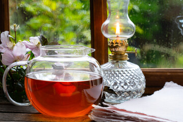 Teapot and a lamp by the window during the rain