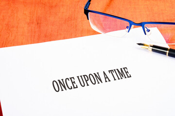 Once upon a time text an inscription on a white sheet on the table near glasses and a fountain pen