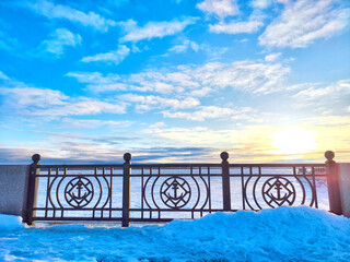 Winter Sunrise Through a Decorative forged Fence. Sunlight piercing through ornate fence on a snowy spring or winter day