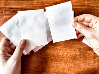 Woman Holding Small White Papers Over a Wooden Surface. Hands presenting several small white papers