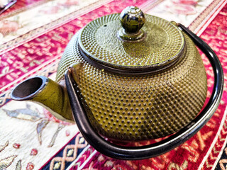 Traditional Cast Iron Teapot on an Oriental Rug. Cast iron teapot poised on a richly patterned rug