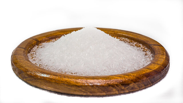 Close-up of monosodium glutamate, MSG in a flat wooden container. It's for seasoning food. White background. Isolated.
