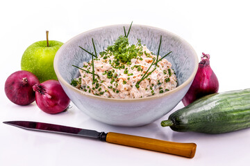 White fish salad in a bowl with apple, onions, cucumber and a knife