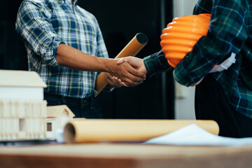 Construction workers, architects and engineers shake hands while working for teamwork and...