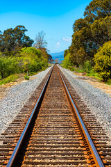 Dead-straight, single-track railroad along the Pacific Coast in Carpinteria, California on a sunny...