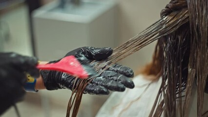 Capturing Beauty: Close-Up of Hair Colorist's Skillful Application of Dye in Salon Setting. High quality 4k footage