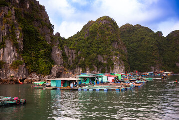 Fototapeta na wymiar Floating fishing village in sea bay in Vietnam, boats and islands