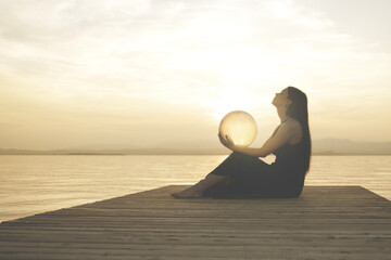 woman protecting a magical sphere illuminated by the sun that releases energy and inner strength,...