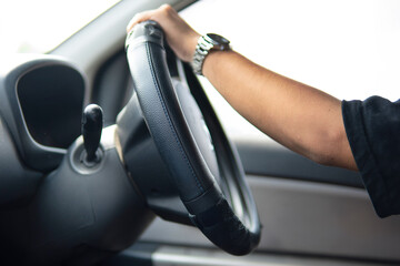 Closeup image of male driver hands holding steering wheel.