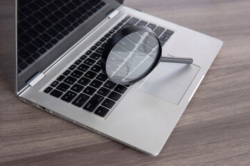 Closeup image of magnifying glass and laptop. Search engine optimization concept. - obrazy, fototapety, plakaty