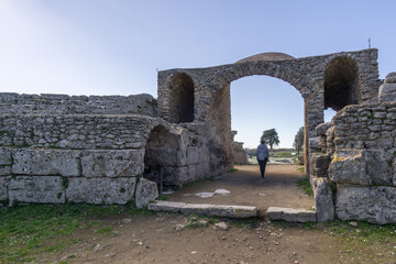 Tourist walking under the arch at ancient Amphitheatre at famous Paestum Archaeological UNESCO World Heritage Site, Salerno, Campania, Italy