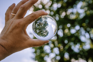 Valmiera, Latvia - August 19, 2023 - A hand holds a crystal ball which reflects an inverted image...