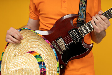Attractive young guy playing guitar in mexican hat
