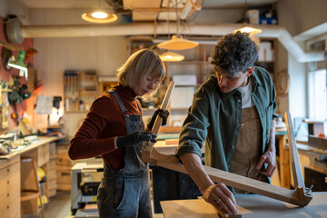 Carpentry workshop, carpenters working together. Professional craftsman and woman assistant...