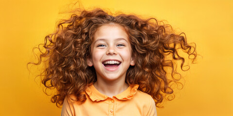 Cute young child  Little girl smiles. Emotion and child development. Little girl smiles while red hair.  A young girl with curly hair is smiling and laughing while wearing a shirt.