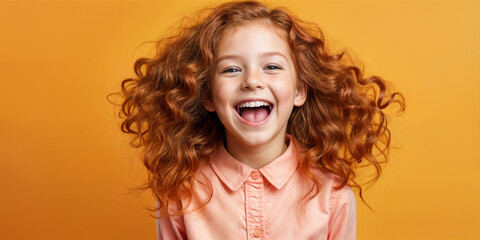 Cute young child  Little girl smiles. Emotion and child development. Little girl smiles while red hair.  A young girl with curly hair is smiling and laughing while wearing a shirt.