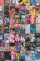 A vibrant assortment of graffiti pieces adorning a long urban wall, portraying different styles and colors.